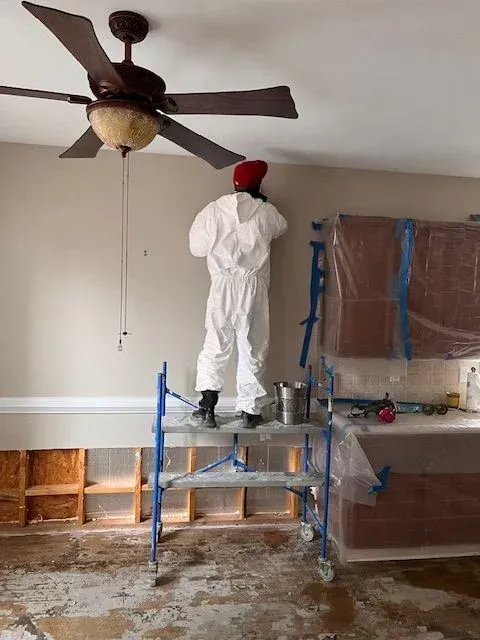 Technician cleaning attic rafters to remove mold and moisture damage